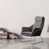 Minimalistische zithoek met grijze designstoel en boekenplank.