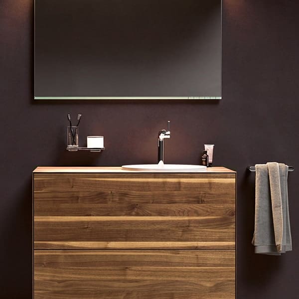 Houten badkamermeubel met spiegel en accessoires in een moderne badkamer.