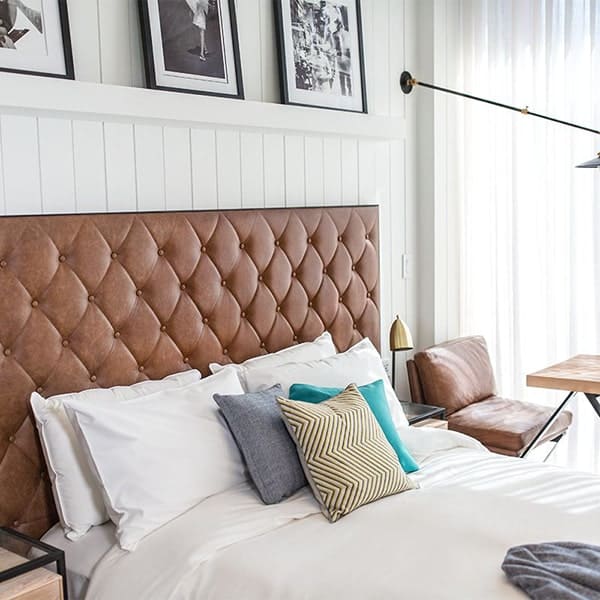 Gezellige slaapkamer met gestoffeerd hoofdeinde en decoratieve kussens.