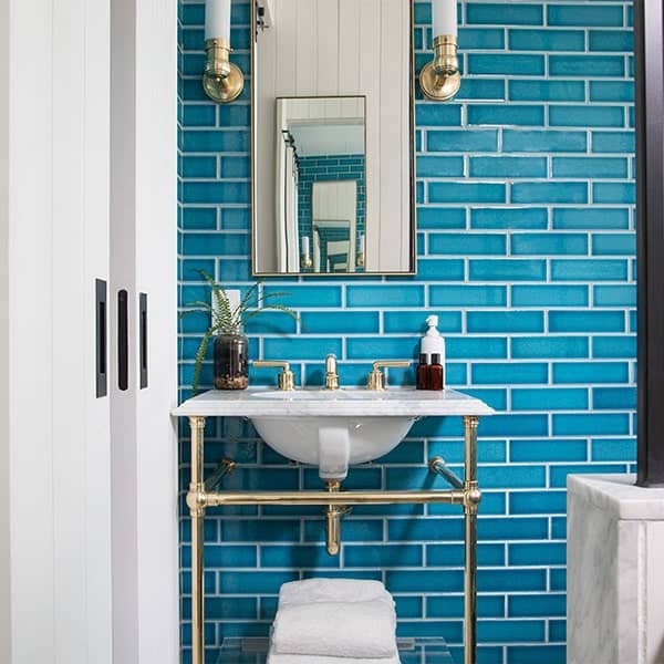 Badkamer met blauwe muurtegels, spiegel en gouden accenten.