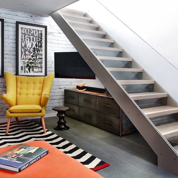 Interieur met moderne trap, gele fauteuil en zwart-wit tapijt.