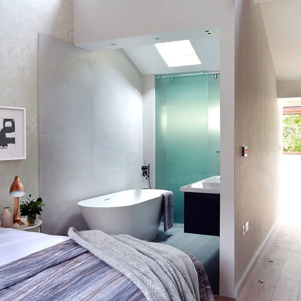 Luxe badkamer met vrijstaand bad en glazen douchewand.