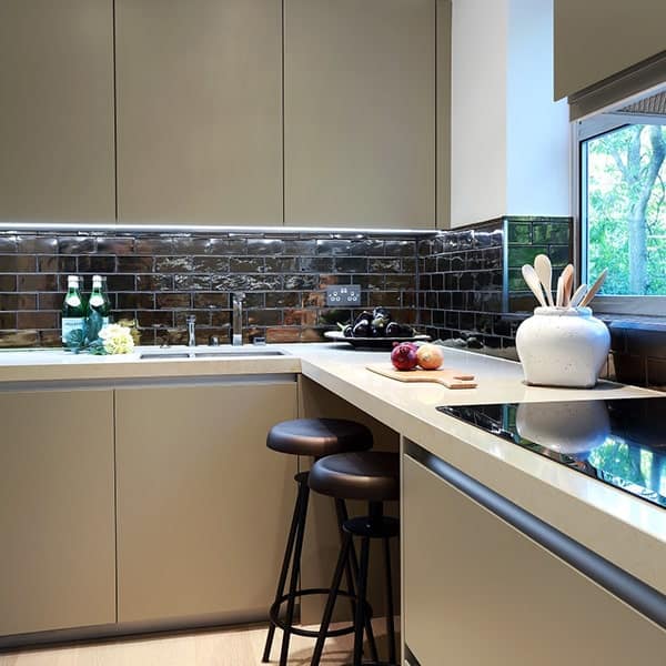 Moderne keuken met beige kasten en zwart tegelwerk achter het aanrechtblad.