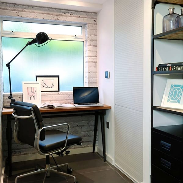 Kantoor met bureau, stoel, laptop en decoratieve kunstwerken.