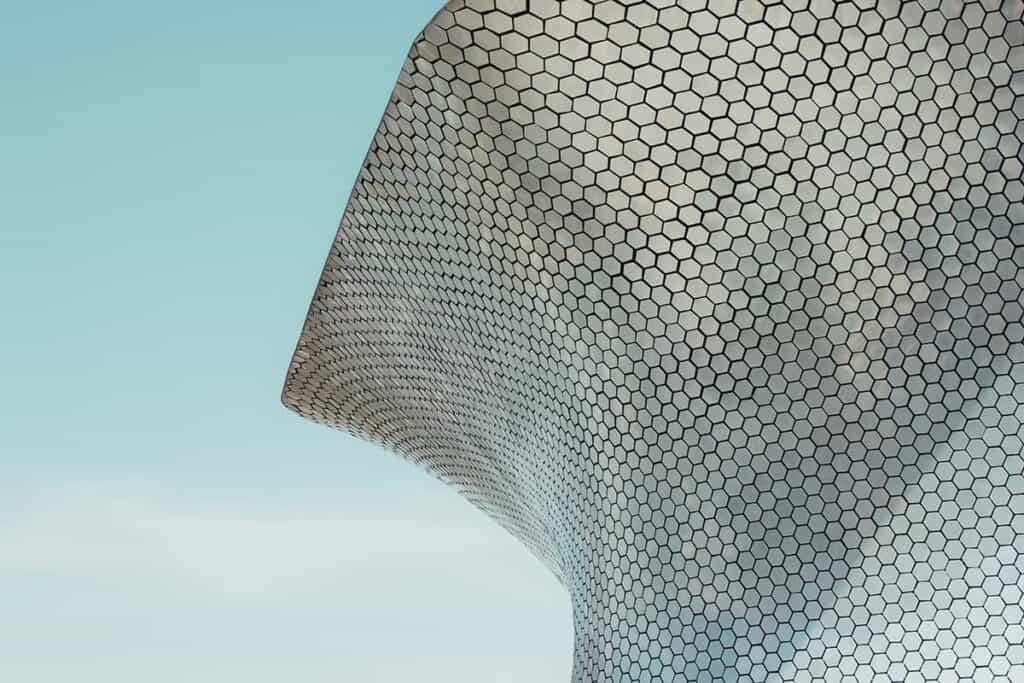 Moderne architectuur met hexagonale gevelpanelen en een blauwe hemel.