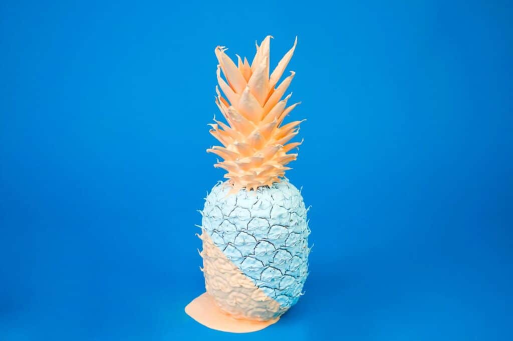 Kunstmatige ananas met een blauwe en witte kleur op een blauwe achtergrond.