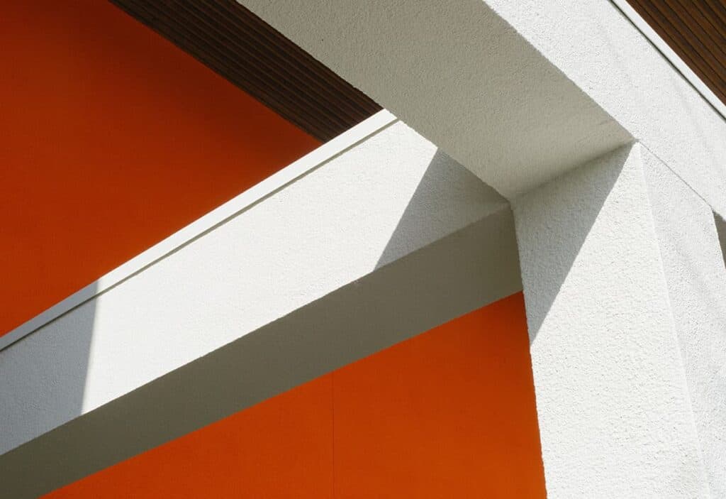 Moderne architectuur met witte en oranje gevels en schaduwpatronen.