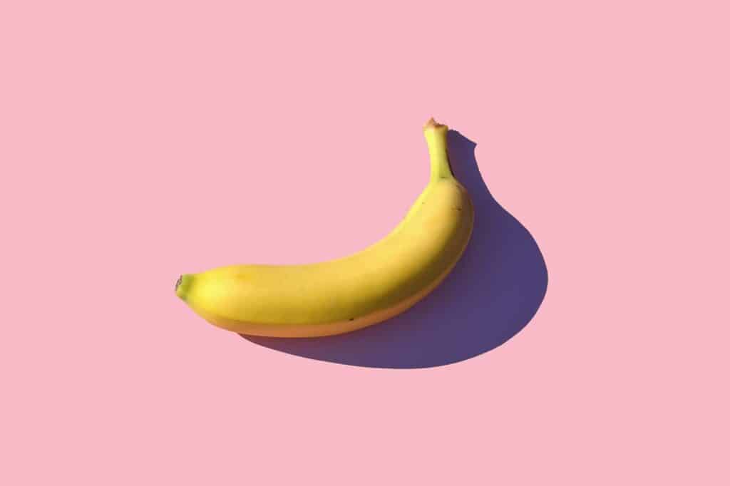 Gele banaan op roze achtergrond, gezond en natuurlijk fruit.