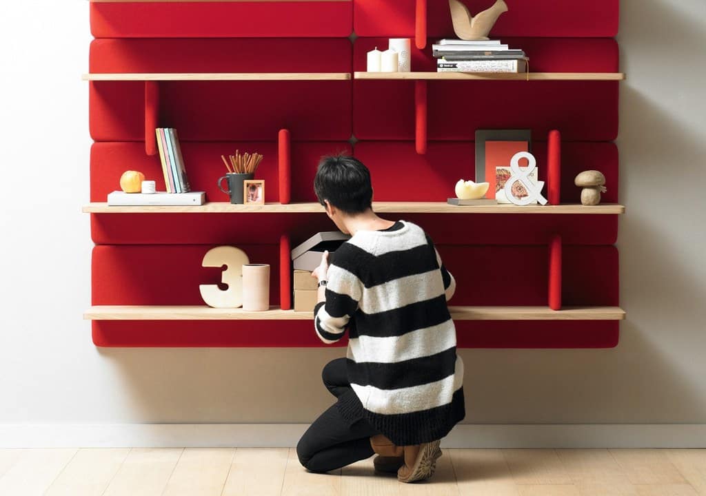 Man bekijkt decoratieve objecten op een rood wandrek in interieur.